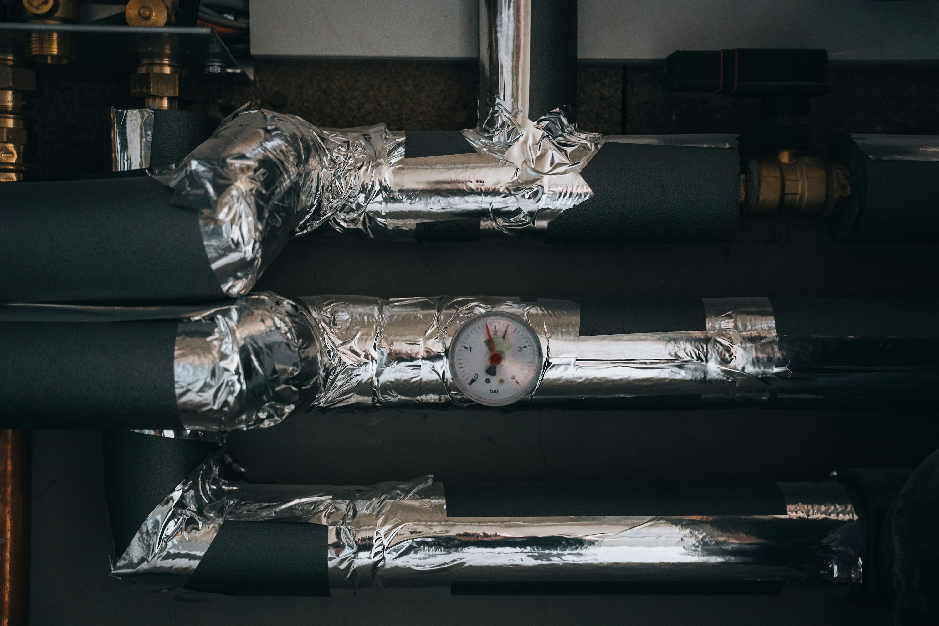 Insulated heating pipes and equipment arranged on a utility-room wall